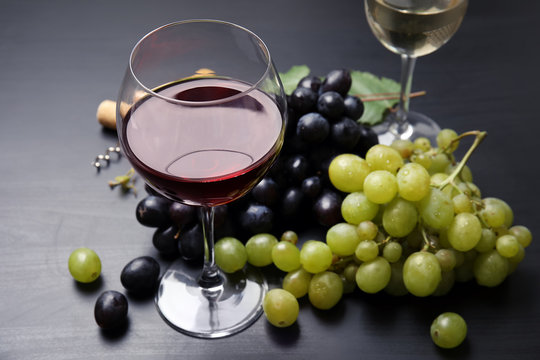 Glass of red wine and fresh ripe juicy grapes on table