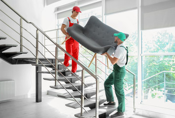 Male movers carrying sofa in new house