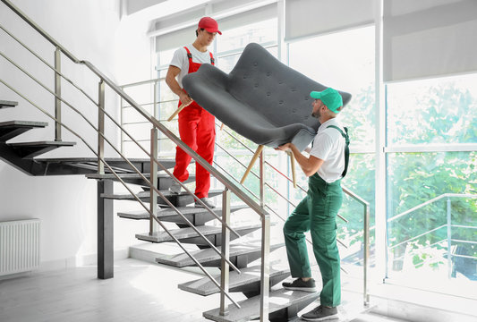 Male Movers Carrying Sofa In New House