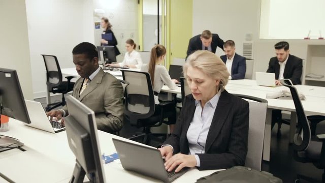 Successful coworkers engaged in business activities in busy open plan office