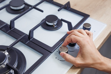 Close up of man's hand set temperature on control panel of hob
