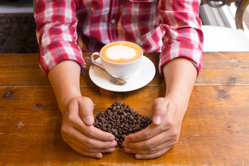 Hand show for love  with coffee on  wooden table. Photograph taken from above, top view with heart coffee