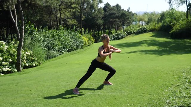 Young woman exercising, stretching and training squatting outdoors. Healthy, fitness, wellness lifestyle. Sport, cardio, workout concept