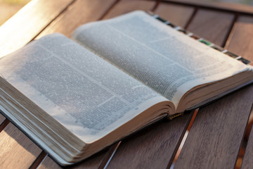 Christian worship and praise. The open bible on a chair in the morning light.