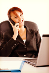 Attractive young woman having negotiations by phone in office