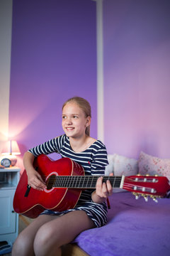 Teenage girl playing a  guitar in her lovely room