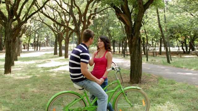 HD Shot of move in on Couple on bikes chatting outdoors.