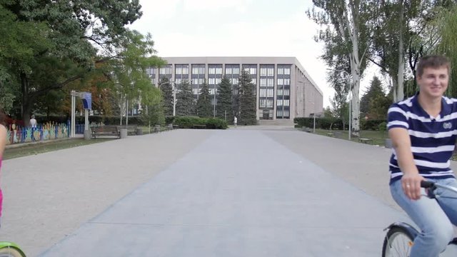 HD A Couple riding bicycles in the park, on block stones moving on the camera