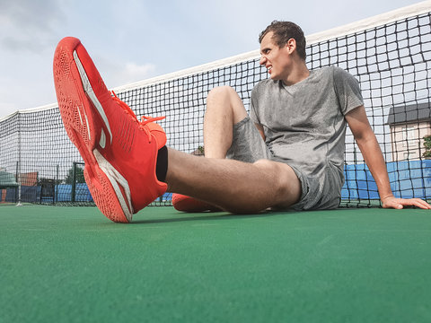 Male tennis player sitting on the ground