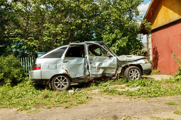 Damaged car after accident near garage in the yard