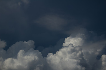 white cumulus clouds on dark blue sky in shadows