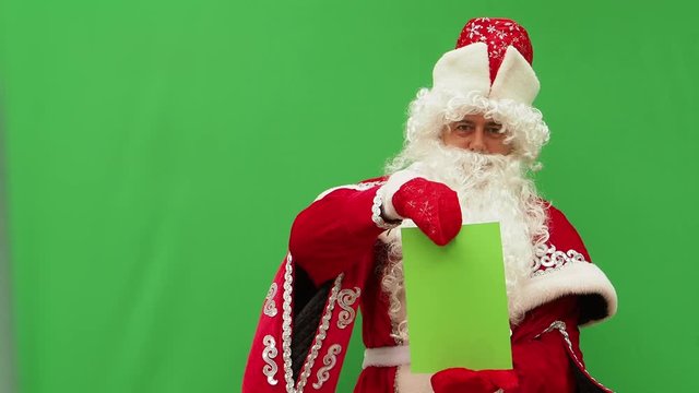 Father Frost holds the form. The New Year's character holds the A4 format model. Green background. An opportunity to insert the design.