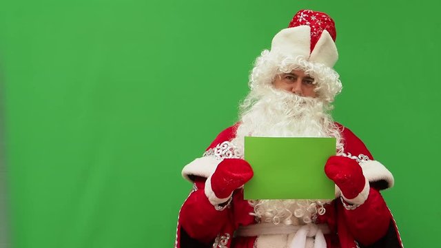 Father Frost holds the form. The New Year's character holds the A4 format model. Green background. An opportunity to insert the design.