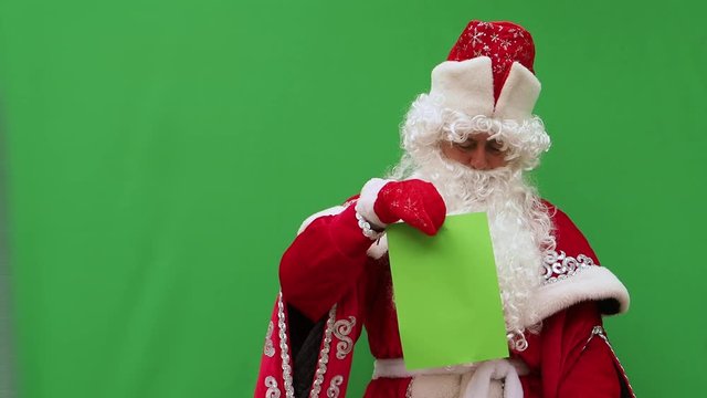 Father Frost holds the form. The New Year's character holds the A4 format model. Green background. An opportunity to insert the design.
