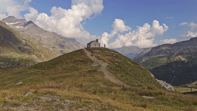 Small church in the alpine panorama. Gran Paradiso National Park - Time lapse. Italy