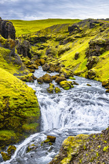 Naklejka na ściany i meble View of cascade of small waterfalls near huge Skogarfoss waterfall on South Iceland