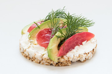 round crisp breads with cheese, tomatoes, dill and avocado on white background
