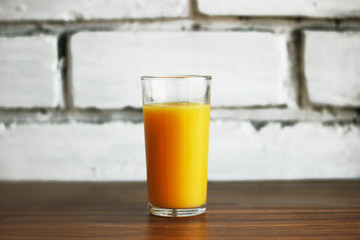 fresh orange juice in a glass on a brick wall background in a loft style