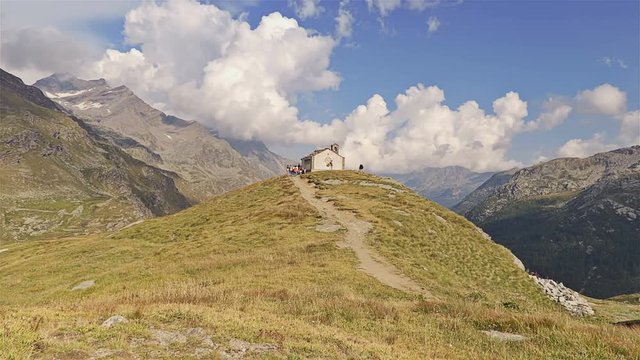 Small church in the alpine panorama. Gran Paradiso National Park - Time lapse. Italy