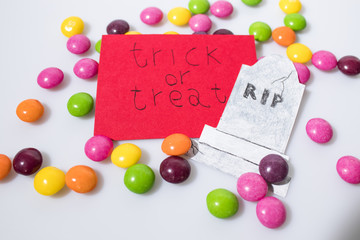 Halloween composition, trick or treat handwritten on a red paper and candies
