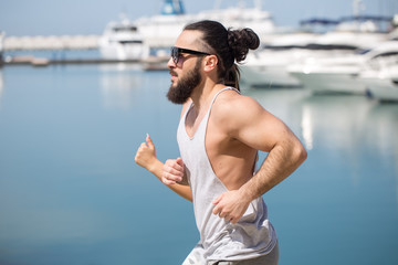 Athlete running man - male runner in San Francisco listening to music on smartphone. Sporty fit young man jogging by San Francisco Bay and Golden Gate Bridge. Jogger training with smart phone armband,