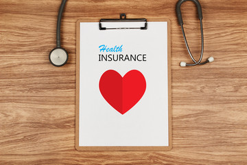 Clipboard with text Health INSURANCE and paper heart with stethoscope on wooden desk, Healthcare and Medical Concept
