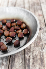 Roast chestnuts in a steel frying pan. Potty with perforated bottom. Wooden background