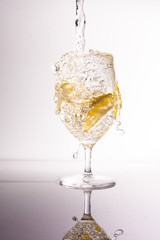 Glass with water and lemons with splashes, refreshment drink. 