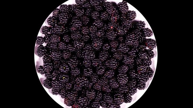 Plate with blackberry rotates on a black Plate with blackberry rotating on a black background close-up

