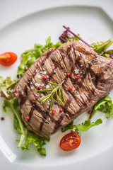 Close-up  juicy flank steak from vegetable salad.