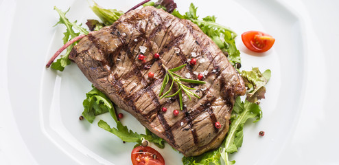 Close-up  juicy flank steak from vegetable salad.