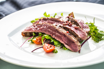 Close-up  juicy flank steak from vegetable salad.