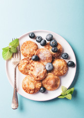 Overhead shoot of dutch mini pancakes called poffertjes with blueberries, sprinkled with powdered sugar. Healthy food concept with copy space.