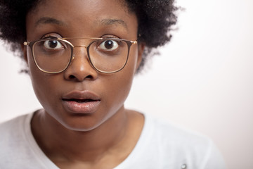 dark-skinned serious attractive lady in big, stylish eyewear looking at the camera. close up...