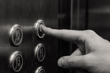 the man presses the elevator button. black and white.