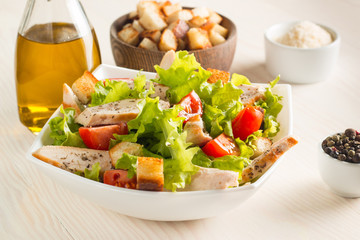 Fresh Greek salad with delicious  ruccola, spinach, cabbage, arugula, feta cheese, red onion and cherry tomato on wooden background. Oil, salt and pepper. Healthy and diet food concept.
