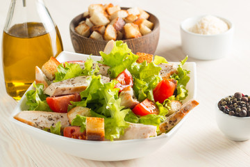 Fresh Greek salad with delicious  ruccola, spinach, cabbage, arugula, feta cheese, red onion and cherry tomato on wooden background. Oil, salt and pepper. Healthy and diet food concept.