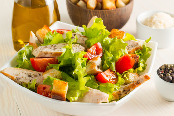 Fresh Greek salad with delicious  ruccola, spinach, cabbage, arugula, feta cheese, red onion and cherry tomato on wooden background. Oil, salt and pepper. Healthy and diet food concept.