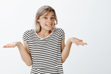 I have no idea really. Carefree cute fair-haired young woman in striped t-shirt shrugging and...