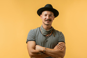 Cheerful hipster man, in stylish casual wear with moustache smiling at camera isolated over yellow...