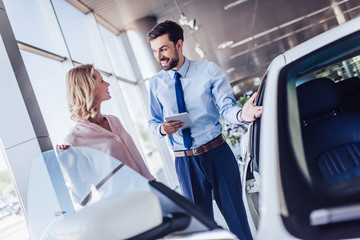 salesman showing new car to female client