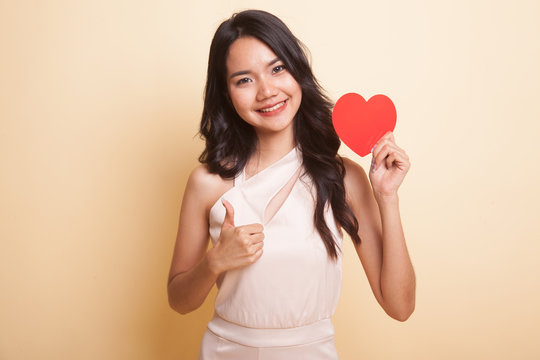 Asian woman thumbs up with red heart.