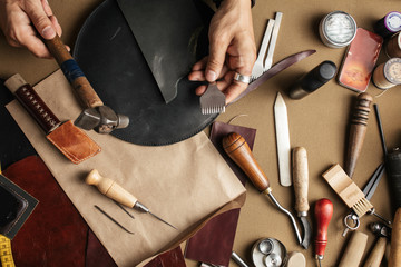 Cropped image of a male shoemaker making design for a new shoes at his workshop. Genuine leather handbag master at work in local workshop. Handmade concept.