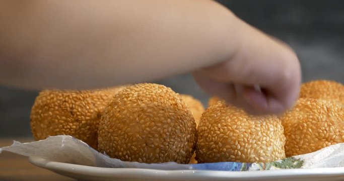 Close view of a kid hand pick up a traditional asian style glutinous rice ball to eat, from a plate, 4K