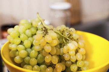 Delicious green grapes are in the yellow bowl in the kitchen. A healthy snack throughout the day, and not just for vegetarians