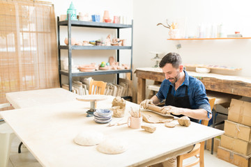Potter Molding Clay With Rolling Pin In Pottery Workshop