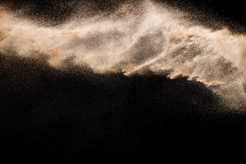 Naklejka na ściany i meble Abstract river sand cloud. Golden colored sand splash against black background. Yellow sand fly wave in the air.