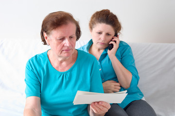 Mutter mit einem Schreiben, ihre Tochter telefoniert