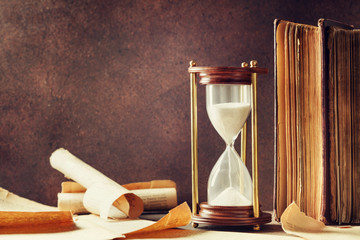 Sand running through the hourglass and old vintage books. Time keeper concept.