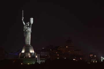 Night landscape with a beautifully lit statue against the backdrop of the city